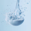 Dynamic close-up of fine blue powder reacting with water, creating a fizzy and effervescent splash.