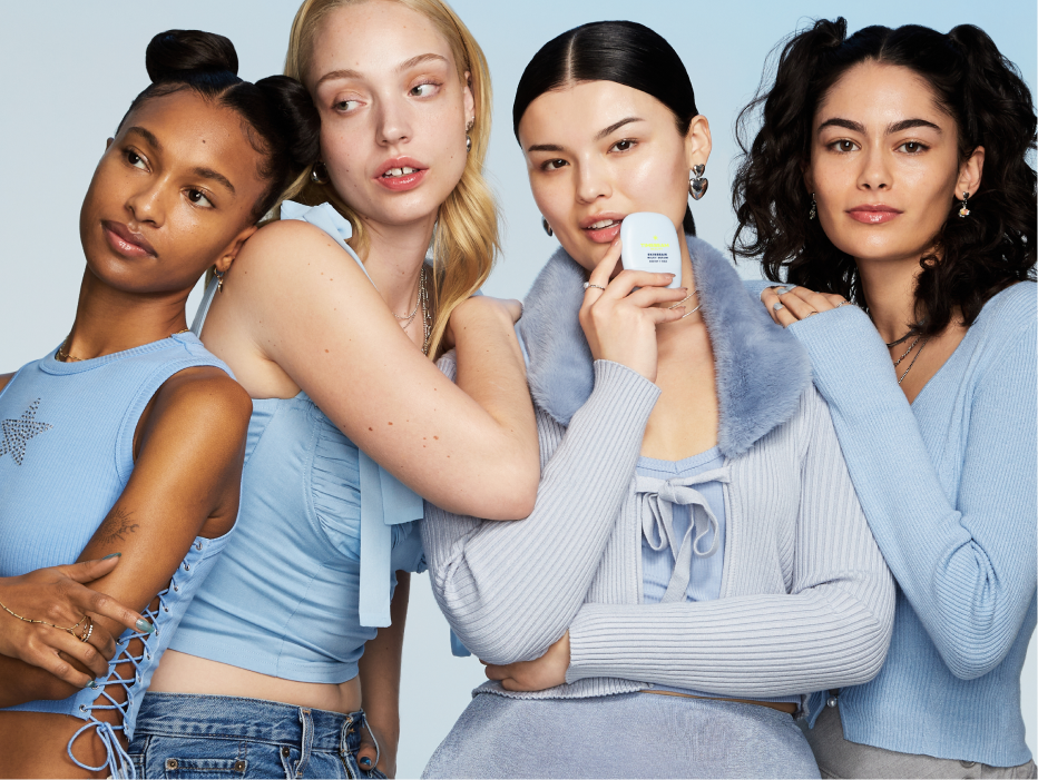 Four women posing, one of them holding a TIMEBEAM skincare balm.