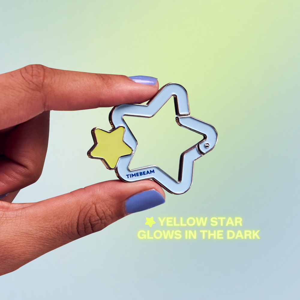 Hand holding a star-shaped carabiner with a yellow star inside, on a gradient background.