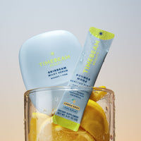 TIMEBEAM Milky Serum and a Bounce Mode supplement pouch in a glass with lemons.