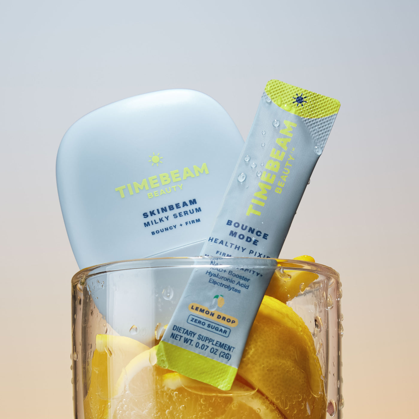 TIMEBEAM Milky Serum and a Bounce Mode supplement pouch in a glass with lemons.