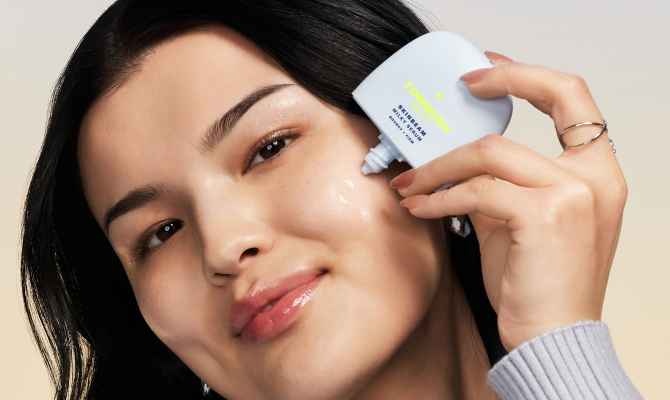 A woman applying TIMEBEAM Milky Serum to her face.