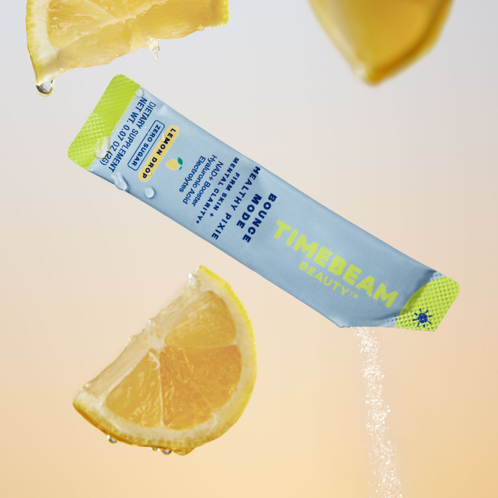 Open pouch of TIMEBEAM supplements drizzling down, surrounded by slices of lemon.
