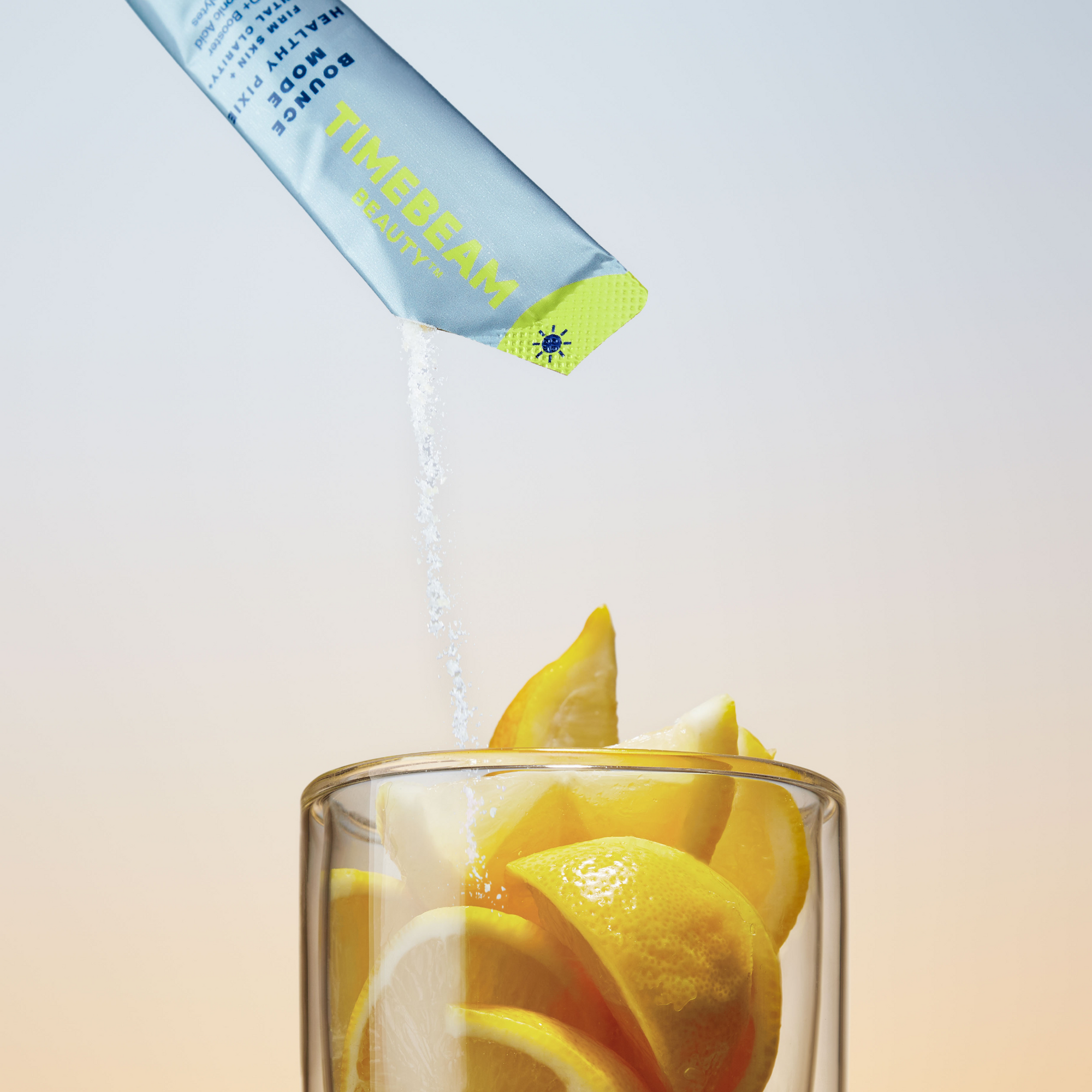 The contents of a TIMEBEAM pouch pour into a glass filled with lemon slices.