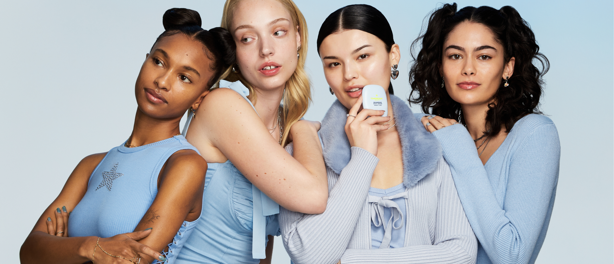 Four women posing, one of them holding a TIMEBEAM skincare balm.