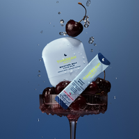 TIMEBEAM Moisture Melt Serum Balm and a Reset Mode supplement pouch, styled with cherries in a glass and water droplets.
