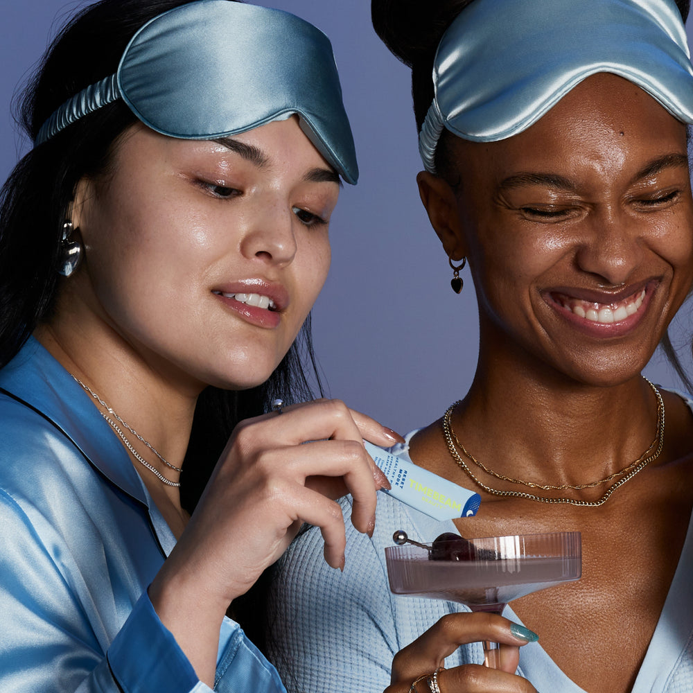 Two women with sleeping masks on their heads, adding TIMEBEAM supplements to a drink.