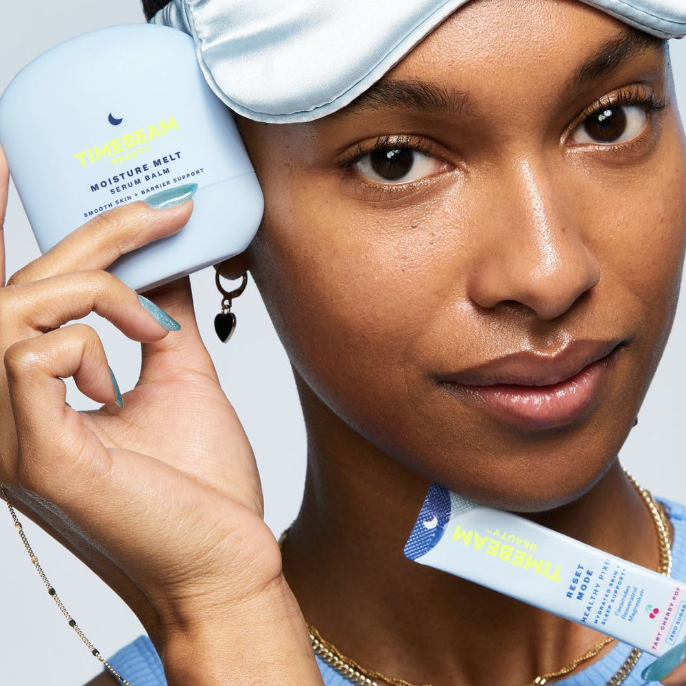 A woman with a sleeping mask on her head, holding TIMEBEAM skincare and supplements.