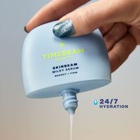 A hand squeezing the content out of a TIMEBEAM Skinbeam Milky Serum bottle, with the text "24/7 hydration".