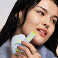 Woman holding Timebeam milky serum and bounce mode pixie stick.