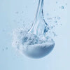 Dynamic close-up of fine blue powder reacting with water, creating a fizzy and effervescent splash.