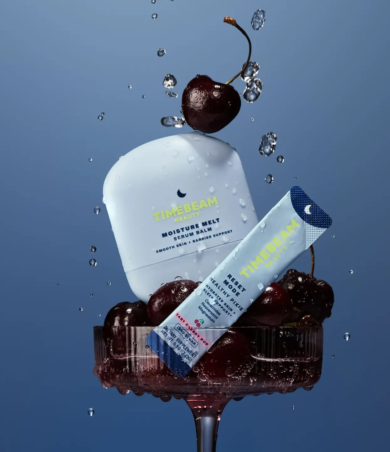 TIMEBEAM Moisture Melt Serum Balm and a Reset Mode supplement pouch, styled with cherries in a glass and water droplets.