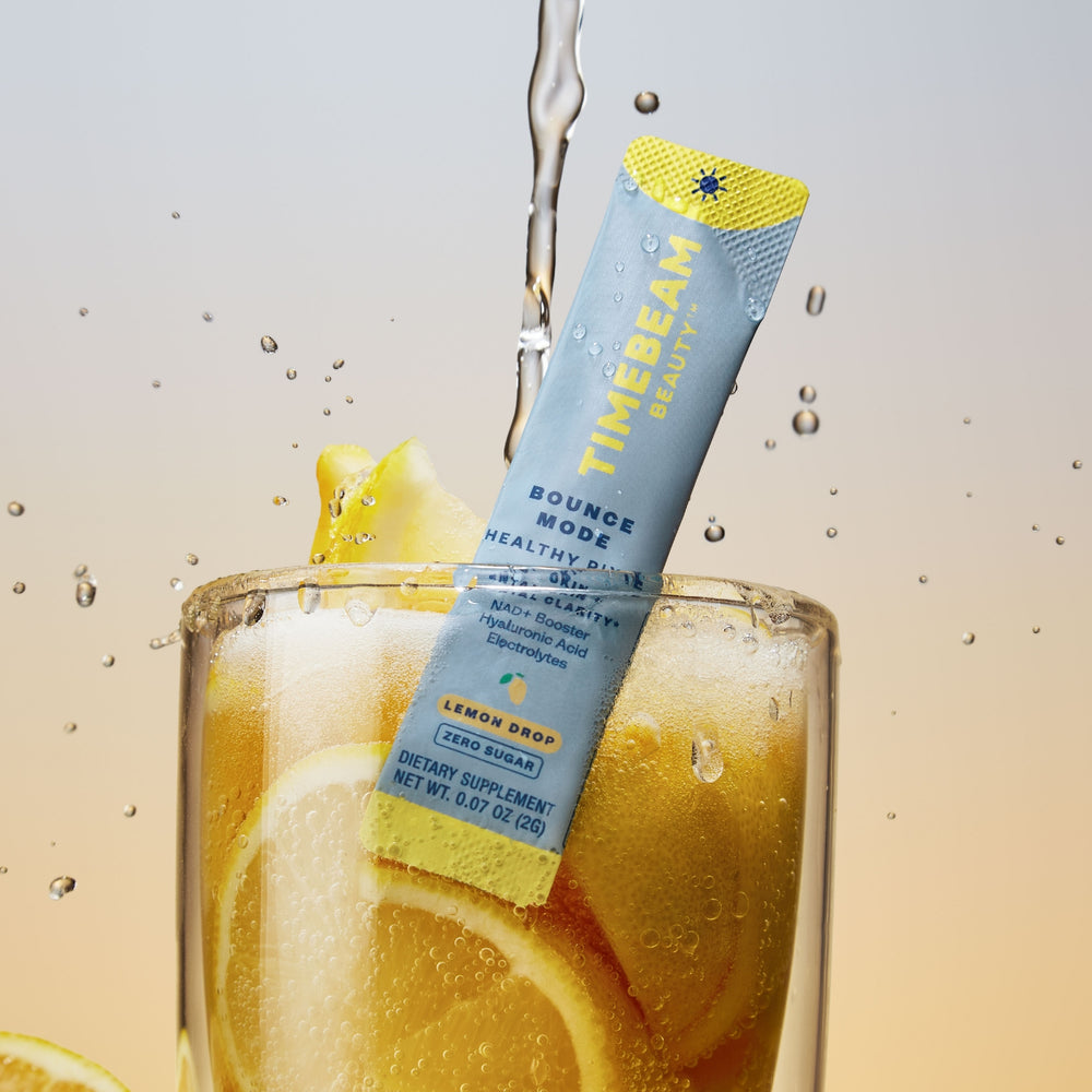 A TIMEBEAM supplement pouch in a glass filled with lemon slices, with water pouring on top.