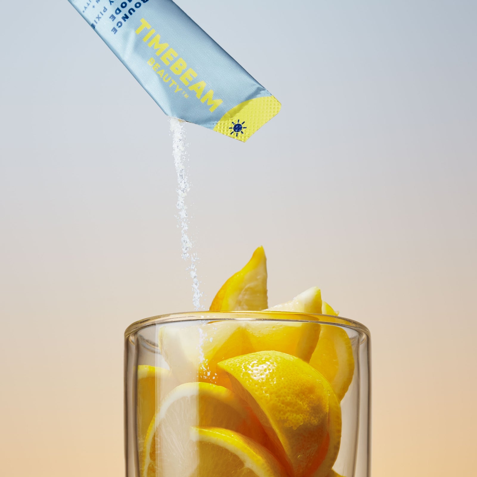 The contents of a TIMEBEAM pouch pour into a glass filled with lemon slices.